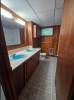Galley style bathroom with two blue inlay sinks and lenolium floors. 