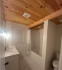 Small bathroom white with cedar lined ceiling features sink and bathtub with shower